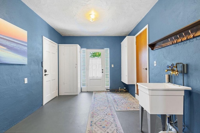 foyer entrance featuring a textured wall, concrete flooring, and a textured ceiling