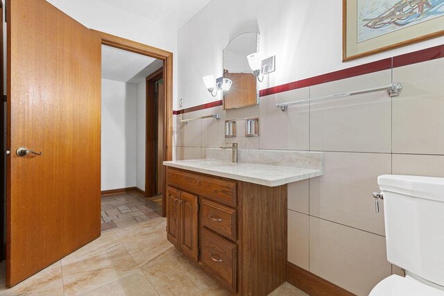 bathroom with vanity, toilet, and tile walls