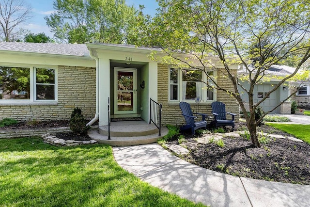 property entrance with a lawn, brick siding, and a shingled roof