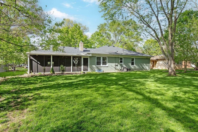 rear view of house featuring a lawn, a chimney, and a sunroom