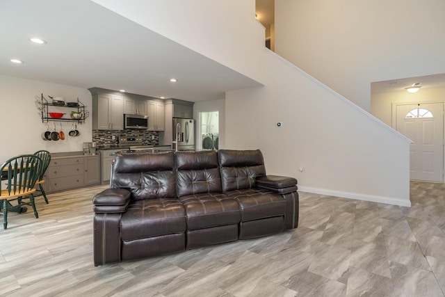 living area with baseboards, stairway, and recessed lighting