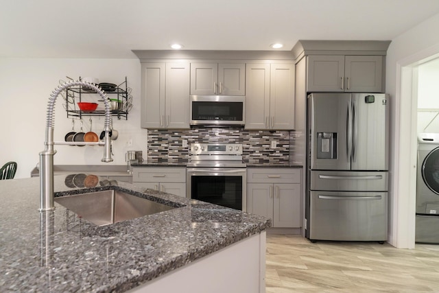 kitchen with dark stone countertops, tasteful backsplash, gray cabinetry, and stainless steel appliances