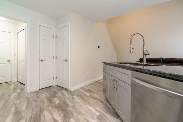 kitchen featuring a sink, baseboards, dark stone counters, and dishwasher