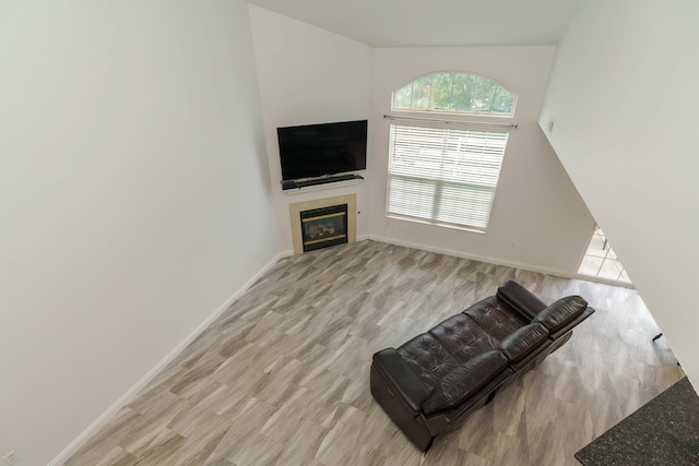 unfurnished living room with light wood-style flooring, a glass covered fireplace, and baseboards