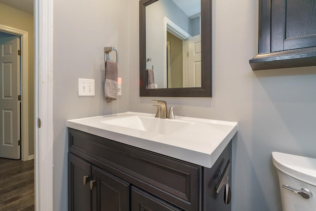 half bath featuring vanity, toilet, and wood finished floors