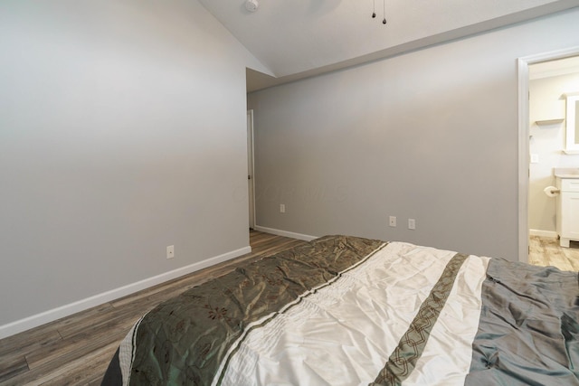 bedroom with lofted ceiling, baseboards, connected bathroom, and wood finished floors