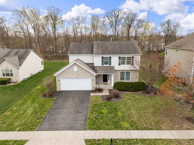 traditional home featuring a front yard, an attached garage, stone siding, driveway, and roof with shingles