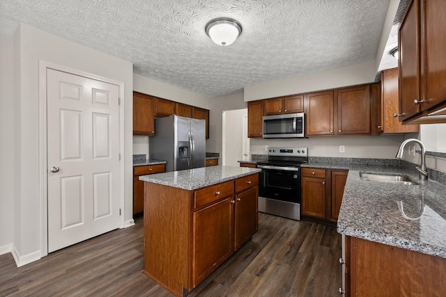 kitchen with dark stone counters, a sink, dark wood-style floors, and stainless steel appliances