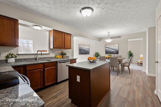 kitchen featuring stainless steel dishwasher, visible vents, wood finished floors, a sink, and dark countertops