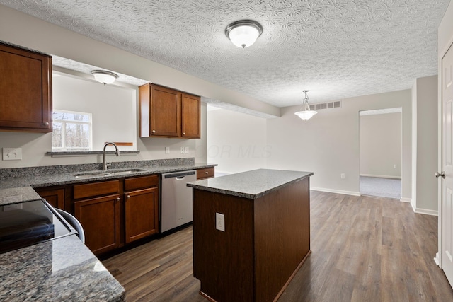 kitchen featuring visible vents, dishwasher, a sink, dark countertops, and dark wood-type flooring