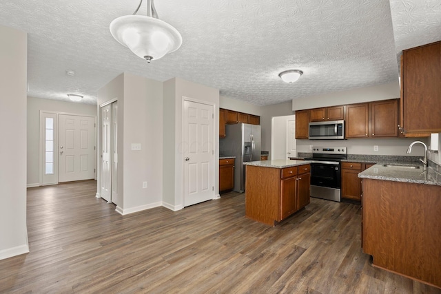 kitchen featuring a sink, appliances with stainless steel finishes, a kitchen island, and dark wood-style floors