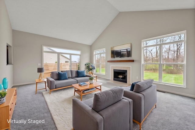 carpeted living area with high vaulted ceiling, a tiled fireplace, visible vents, and baseboards
