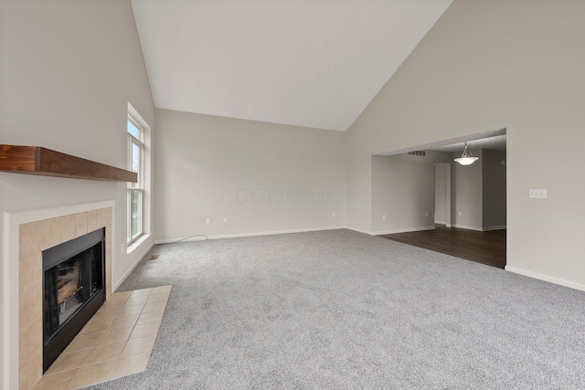 unfurnished living room with high vaulted ceiling, carpet, a tile fireplace, and baseboards