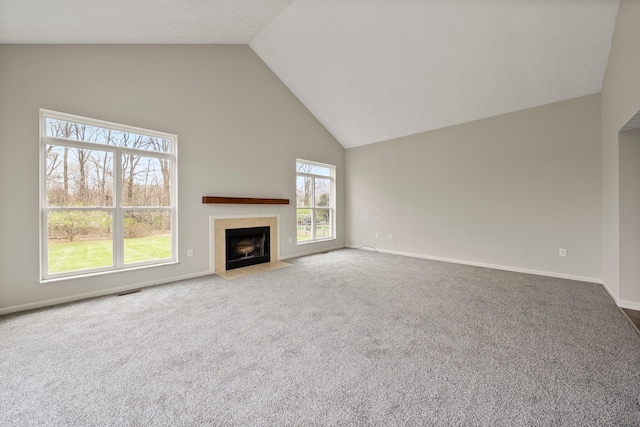 unfurnished living room with high vaulted ceiling, a tiled fireplace, carpet flooring, and baseboards