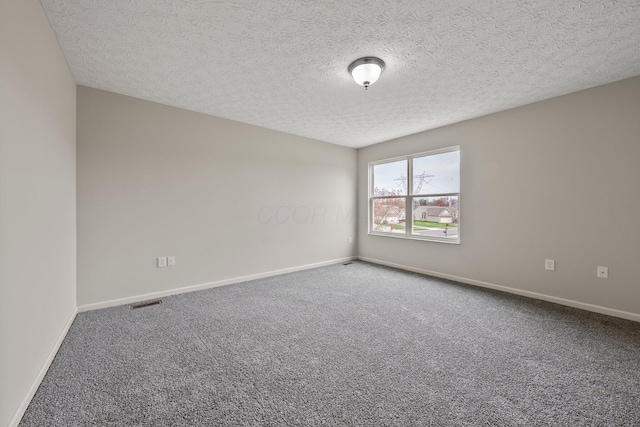 empty room with a textured ceiling, carpet flooring, and baseboards