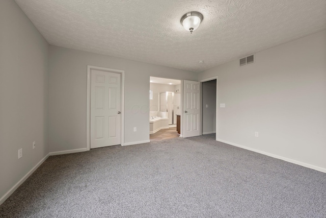 unfurnished bedroom with carpet, visible vents, baseboards, and a textured ceiling