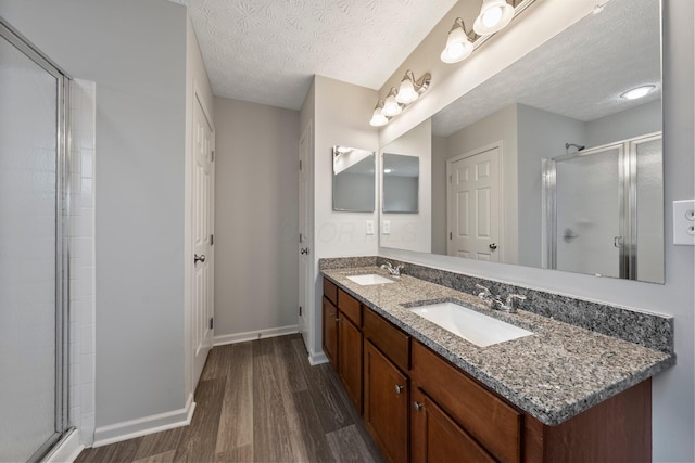 full bath featuring a shower stall, wood finished floors, a sink, and baseboards