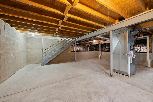 unfinished basement featuring heating unit and stairs