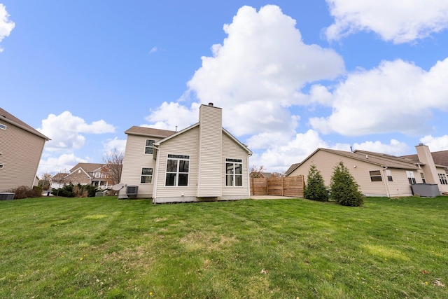 rear view of house featuring fence, a lawn, and a chimney