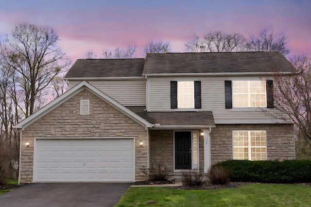traditional home with a shingled roof, stone siding, a garage, and aphalt driveway