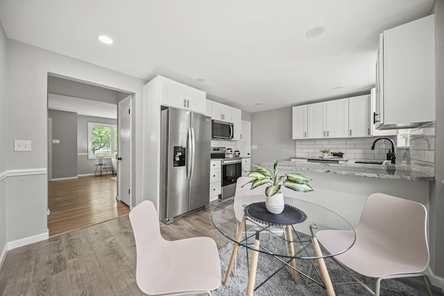 2960 Berwick Blvd, Columbus, OH 43209 - kitchen with stainless steel appliances, a sink, tasteful backsplash, white cabinetry, and a peninsula