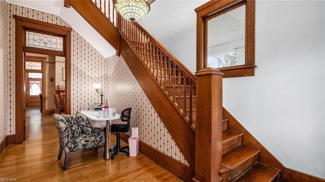 stairs featuring plenty of natural light, baseboards, wallpapered walls, and wood finished floors