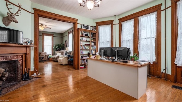 home office featuring a chandelier, hardwood / wood-style floors, visible vents, and a premium fireplace