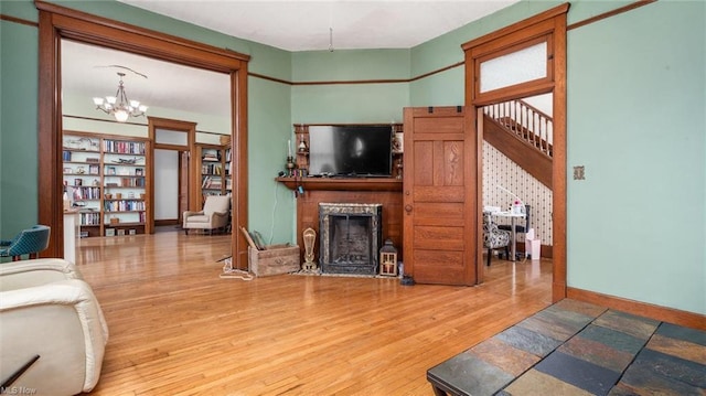 living room with wood finished floors, a fireplace, baseboards, and a notable chandelier