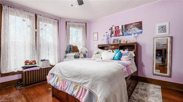 bedroom featuring ceiling fan, radiator, and wood finished floors