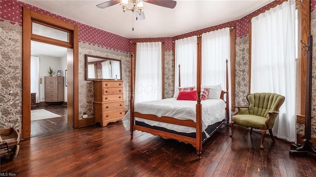 bedroom with hardwood / wood-style floors, wallpapered walls, and a ceiling fan