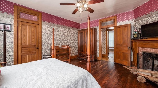 bedroom featuring baseboards, hardwood / wood-style floors, a fireplace, and wallpapered walls