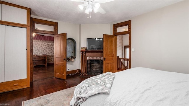 bedroom featuring a closet, dark wood-style flooring, ceiling fan, and a fireplace