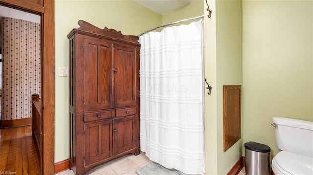 full bathroom featuring tile patterned flooring, baseboards, and toilet