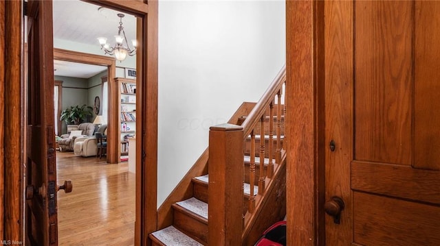 stairs featuring a notable chandelier and wood finished floors