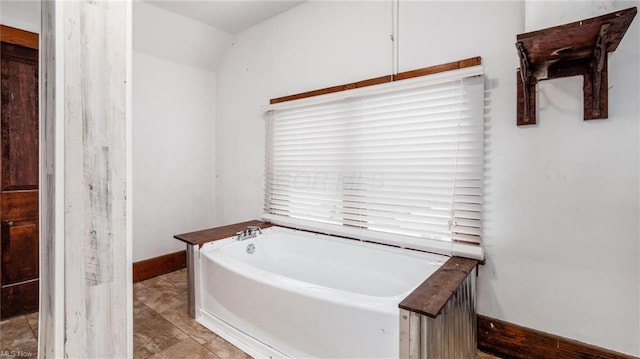 bathroom with a garden tub and baseboards