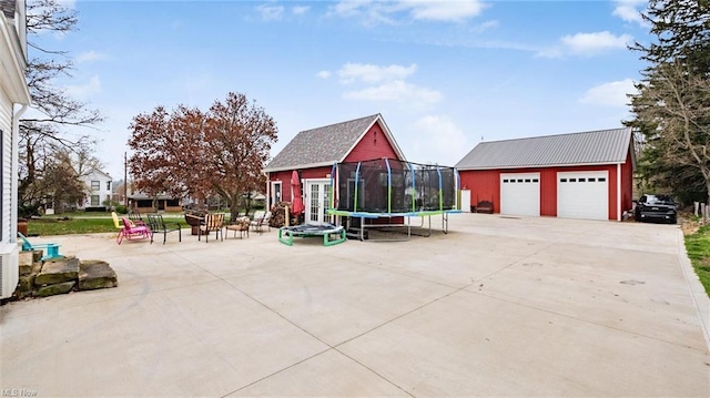 exterior space with a trampoline, an outdoor structure, and a garage