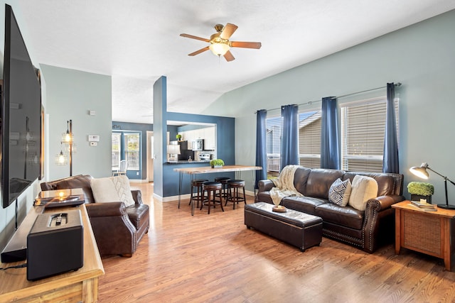 living area with light wood-style floors, lofted ceiling, a ceiling fan, and baseboards