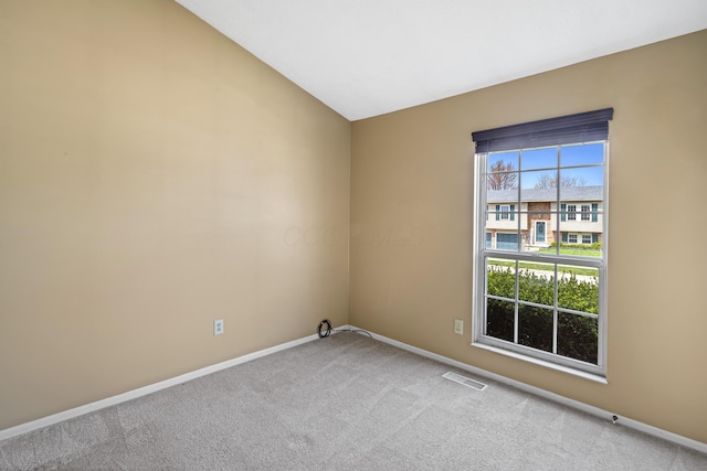 carpeted spare room featuring baseboards, vaulted ceiling, and visible vents