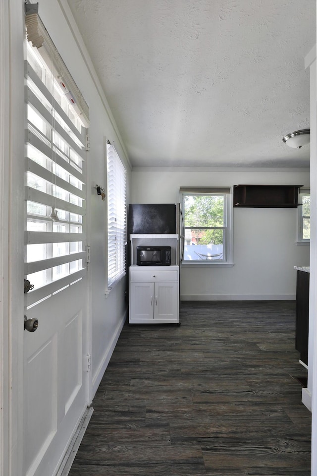 3113 Oaklawn St, Columbus, OH 43224 - unfurnished living room with plenty of natural light, baseboards, a textured ceiling, and dark wood-type flooring