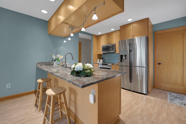 441 Gentlewind Dr, Westerville, OH 43081 - kitchen featuring decorative backsplash, a kitchen breakfast bar, light wood-type flooring, a peninsula, and stainless steel appliances