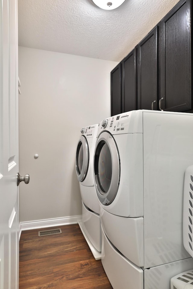 6134 Glade Run Rd, Hilliard, OH 43026 - laundry area featuring cabinet space, dark wood-style floors, washer and dryer, baseboards, and a textured ceiling