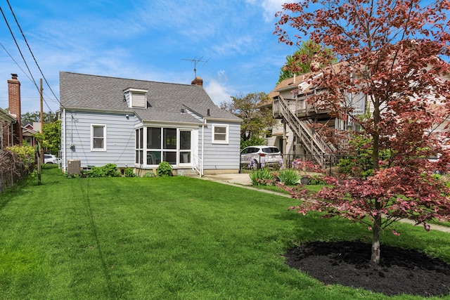 rear view of house featuring a sunroom, a shingled roof, and a chimney