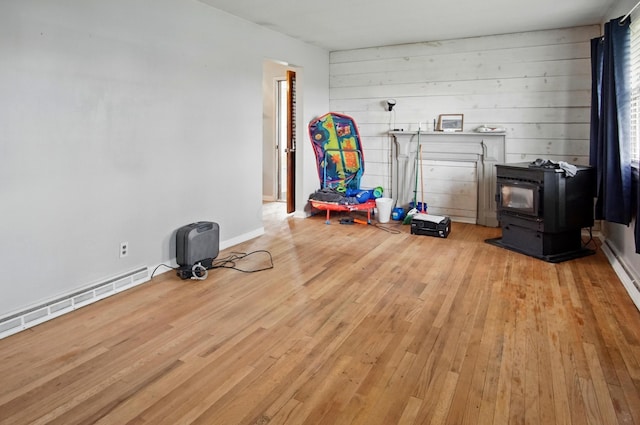 5235 Raiders Rd, Frazeysburg, OH 43822 - playroom with light wood-style flooring, a wood stove, and a baseboard heating unit