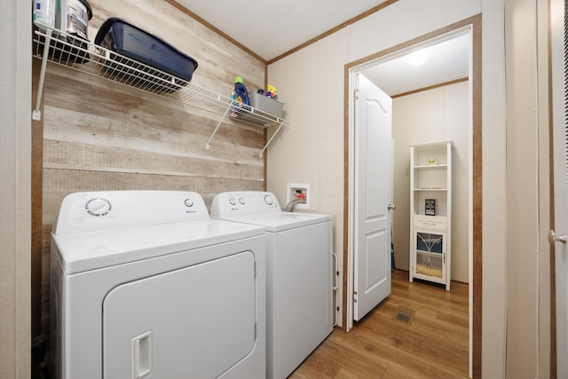 laundry area featuring visible vents, ornamental molding, light wood finished floors, and washer and dryer