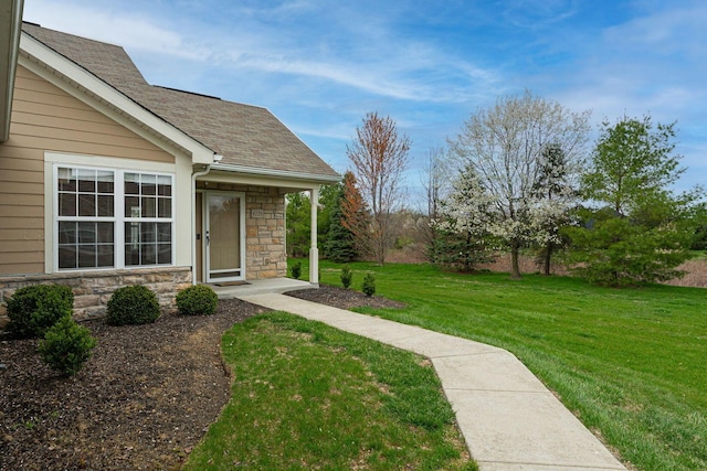 doorway to property with a lawn, stone siding, and a shingled roof