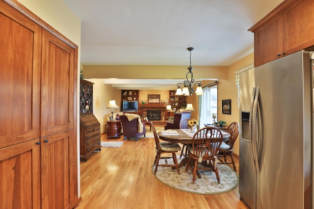 5580 Millington Rd, Columbus, OH 43235 - dining room with light wood-style flooring, a notable chandelier, and a brick fireplace