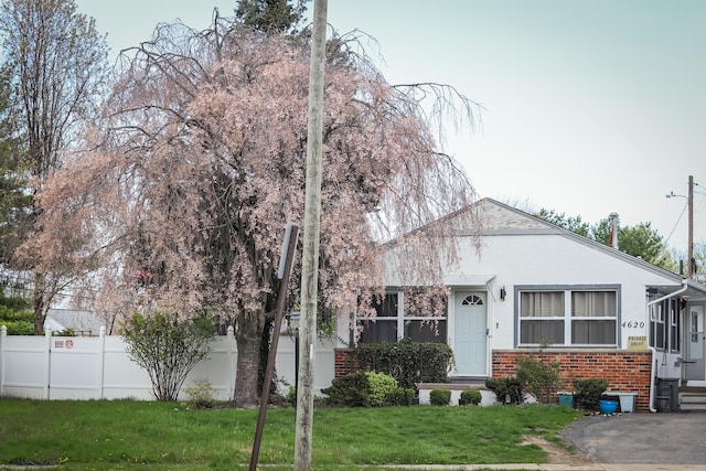 view of front of home with brick siding, a front yard, and fence