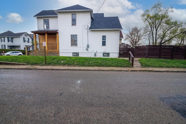 exterior space featuring stairway, roof with shingles, and fence