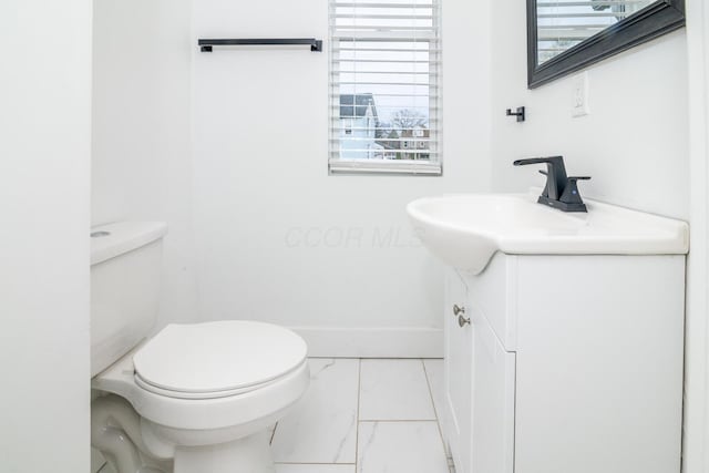 half bath featuring marble finish floor, toilet, a healthy amount of sunlight, and vanity