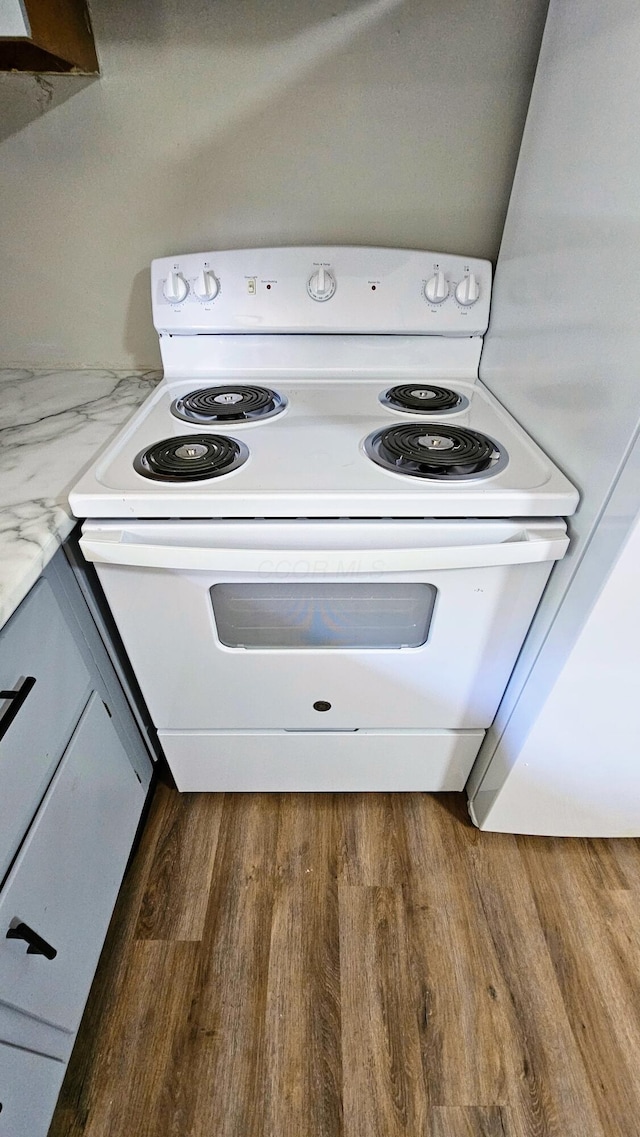 interior details featuring white electric range, wood finished floors, and light stone countertops